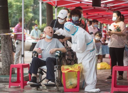 (miniature) Un professionnel de la santé prélève un échantillon de gorge sur un résident pour le test d'acide nucléique de la COVID-19 à Wuhan