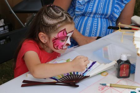 (miniature) Une enfant peint sur un éventail traditionnel chinois lors du deuxième festival des bateaux-dragons à Sofia