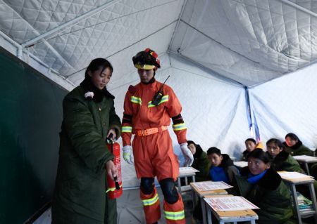 (miniature) Curmey Drolma essaie d'utiliser un extincteur sous la direction d'un pompier à l'intérieur d'une tente au district de Maduo de la préfecture autonome tibétaine de Golog