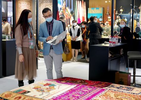 (miniature) Un membre du personnel discute avec une visiteuse de tapis de laine fabriqués à la main lors de la 4e édition de l'Exposition internationale d'importation de la Chine (CIIE) à Shanghai