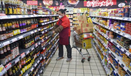 (miniature) Une employée met des marchandises en rayon dans un supermarché de l'arrondissement de Tianshan