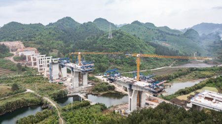 (miniature) Photo aérienne prise par un drone le 17 avril 2024 montrant le pont de la rivière Bailong sur le tracé de l'autoroute Guiyang-Pingtang en construction dans la province chinoise du Guizhou (sud-ouest)
