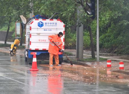 (miniature) Une agente d'entretien de la voirie nettoie du gravier dans une rue inondée de Nanning