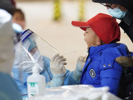 (miniature) Un travailleur médical prélève un échantillon sur un enfant dans un site de dépistage du COVID-19 de l'arrondissement de Daxing