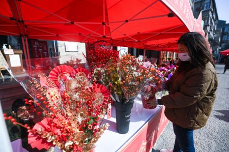 (miniature) Une femme achète des fleurs lors d'un festival d'achats dans le bourg de Pingyao de l'arrondissement de Yuhang