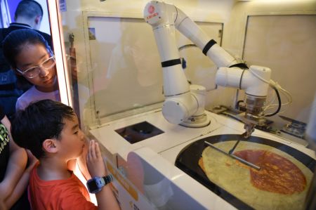 (miniature) Des visiteurs regardent un robot préparant des Jian Bing