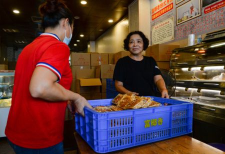 (miniature) Un membre du personnel transporte des gâteaux de lune dans un magasin de gâteaux de lune à la mode de Hainan