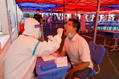 (miniature) Un professionnel de la sant&eacute; pr&eacute;l&egrave;ve un &eacute;chantillon par &eacute;couvillon sur un habitant dans un site de test d'acide nucl&eacute;ique de la COVID-19 de l'arrondissement de Guangling
