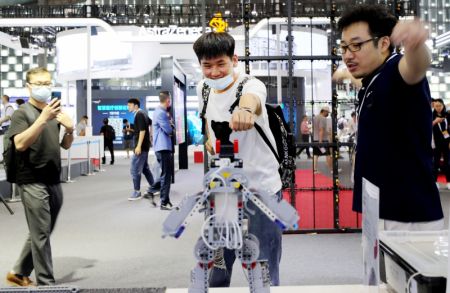 (miniature) Un visiteur (au centre) essaie un robot de détection de mouvement à la Conférence mondiale sur l'intelligence artificielle 2021 à Shanghai