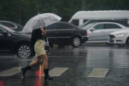 (miniature) Une personne marche près d'une station de métro sous la pluie