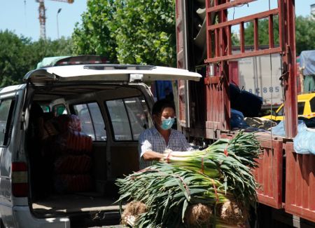 (miniature) Un marchand de légumes décharge des poireaux sur l'un des cinq sites de commerce provisoire désignés à la suite de la suspension du marché de gros de Xinfadi
