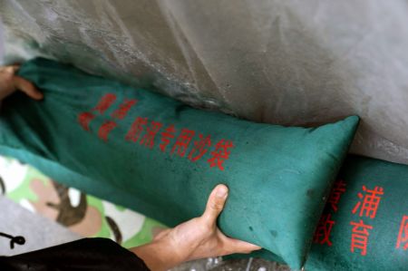 (miniature) Un employé empile des sacs de sable pour renforcer la protection contre les inondations dans une école primaire dans l'arrondissement de Huangpu