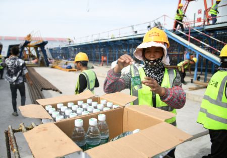 (miniature) Une ouvrière prend une bouteille d'eau sur un chantier dans l'arrondissement de Baqiao