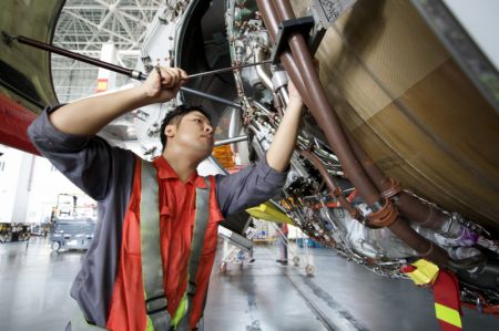 (miniature) Un technicien de HNA Technic procède au changement d'une pièce de moteur d'un avion entrant à la base de maintenance aéronautique du Port de libre-échange de Hainan à Haikou