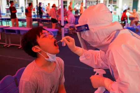 (miniature) Un professionnel de la santé prélève un échantillon par écouvillon sur un habitant dans un site de test d'acide nucléique de la COVID-19 de l'arrondissement de Guangling