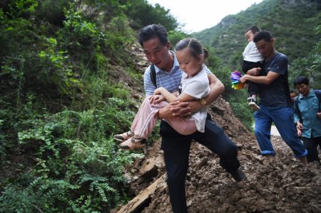 (miniature) Des responsables du village et des parents marchent sur une route endommagée avec des enfants dans les bras à Heping