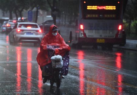 (miniature) Une personne conduit son vélo électrique sous la pluie dans l'arrondissement de Haidian