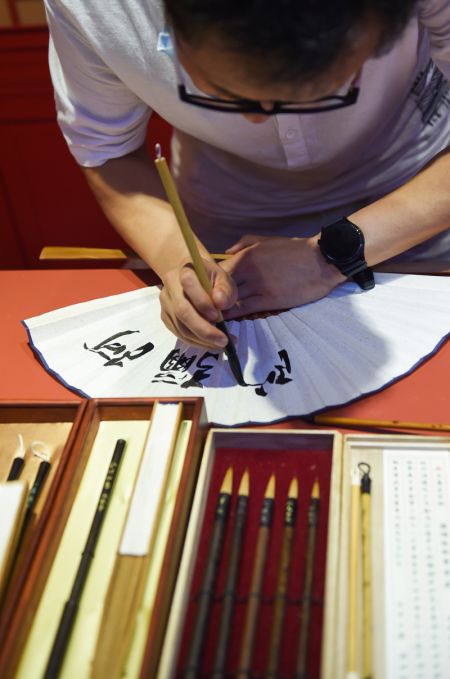 (miniature) Un exposant présente la calligraphie sur un éventail lors de la deuxième Exposition internationale des produits de consommation de Chine
