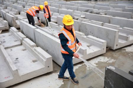 (miniature) Des ouvriers pulv&eacute;risent de l'eau sur des &eacute;l&eacute;ments pr&eacute;fabriqu&eacute;s pour la construction de la ligne ferroviaire &agrave; grande vitesse Guiyang-Nanning &agrave; Dushan
